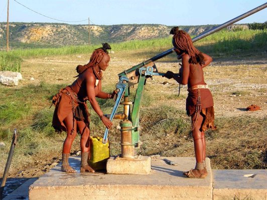Himbakvinnor som reparerar en handpump med stora rörtänger.